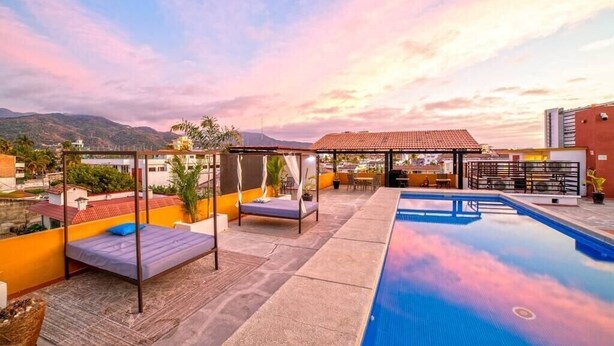 A rooftop pool area with a bed, lounge chairs, and a covered seating area. - Perfect for couples! Great location in Versalles! (Puerto Vallarta)