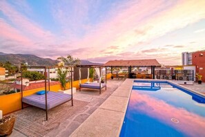 A rooftop pool area with a bed, lounge chairs, and a covered seating area. - Perfect for couples! Great location in Versalles! (Puerto Vallarta)