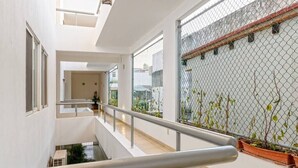 A multi-level indoor space with a metal railing, potted plants, and a view through a chain-link fence. - Perfect for couples! Great location in Versalles! (Puerto Vallarta)