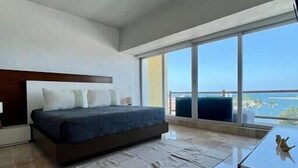 Ein modernes Schlafzimmer mit einem großen Bett, einem Flachbildfernseher und Blick auf das Meer.