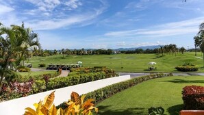 A golf course with a clear sky, palm trees, and a well-maintained lawn. - Wellness apartment | Golf Club, pool and spa (Nuevo Vallarta)