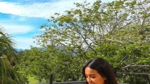 A person seated at a round table with a clock, outdoors with greenery and a clear sky in the background. - Wellness apartment | Golf Club, pool and spa (Nuevo Vallarta)
