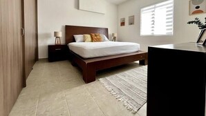 A bedroom with a bed, nightstands, a ceiling fan, a window with blinds, and a desk with a chair.