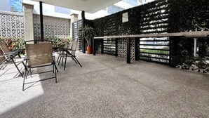 An outdoor patio area with a table and chairs, a potted plant, and a decorative wall.
