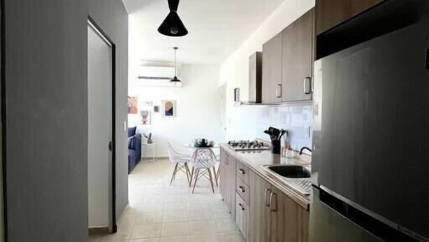 A modern kitchen with dark wooden cabinets, a stainless steel refrigerator, and a black pendant light.