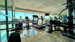 Un gimnasio con cintas de correr, elípticas y equipo de pesas.