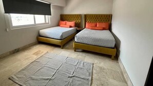 Un dormitorio con dos camas, una ventana con persiana, una alfombra y una lámpara en el techo.