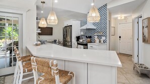 Una cocina moderna con una isla grande, armarios blancos y un salpicadero con diseño.