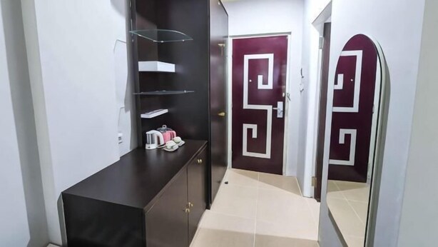 A hallway with a dark-colored console table, a white door with a geometric design, and a mirror reflecting part of the room. - RedDoorz @ Brother Homestay Kupang (Kupang)