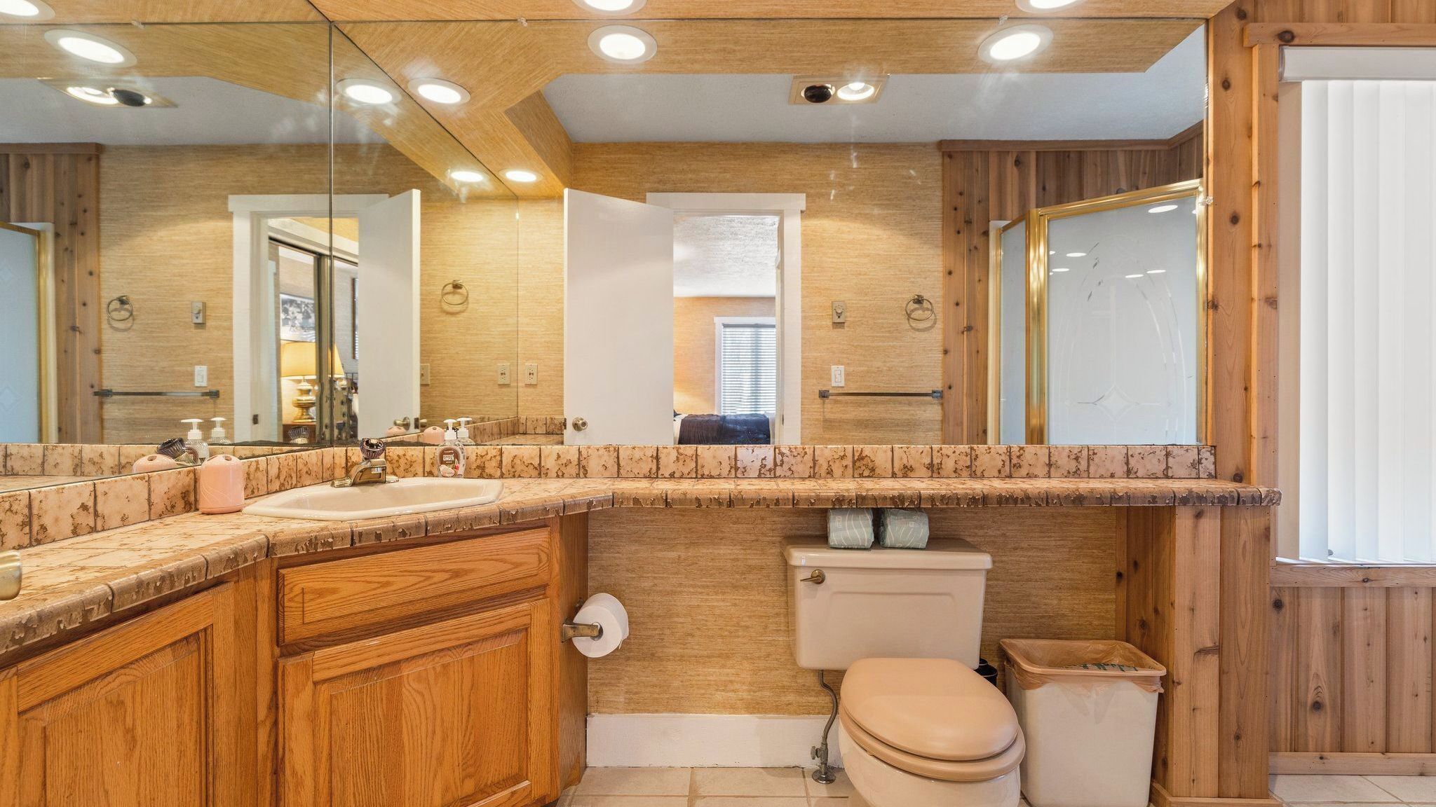 Ein Badezimmer mit Holzschränken, einem Waschbecken, einer Toilette und einem Spiegel.