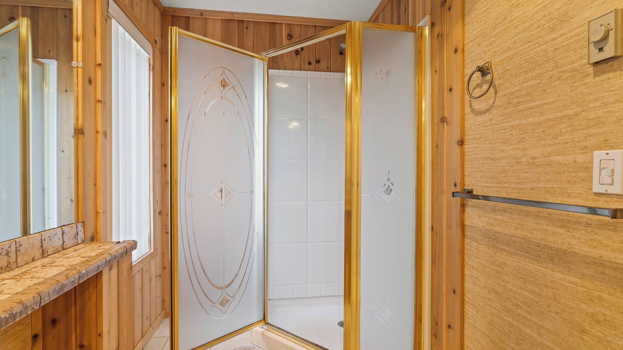 Un interior de madera con ducha, espejo y un interruptor de luz en la pared.