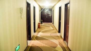A hotel hallway with doors on both sides, a carpeted floor, and a light fixture on the ceiling.