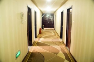 Un pasillo de hotel con puertas a ambos lados, piso alfombrado y una lámpara en el techo.
