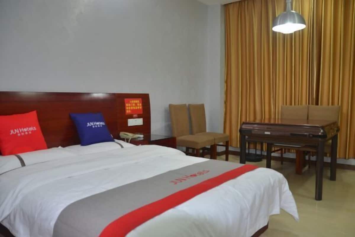 A hotel room with a bed, a desk, a chair, and a piano.