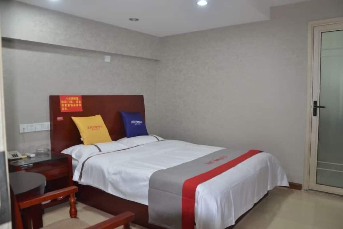 A hotel room with a bed, a desk, and a chair.