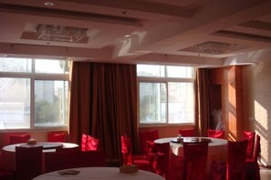 A dining area with round tables and chairs, large windows, and curtains. - Shenzhou Business Hotel (Jinhu)