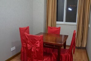 A dining area with a wooden table and four chairs, each with a red cover. - Shenzhou Business Hotel (Jinhu)