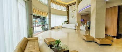 A spacious lobby with a curved ceiling, a reception desk, and a seating area with leather sofas and ottomans.