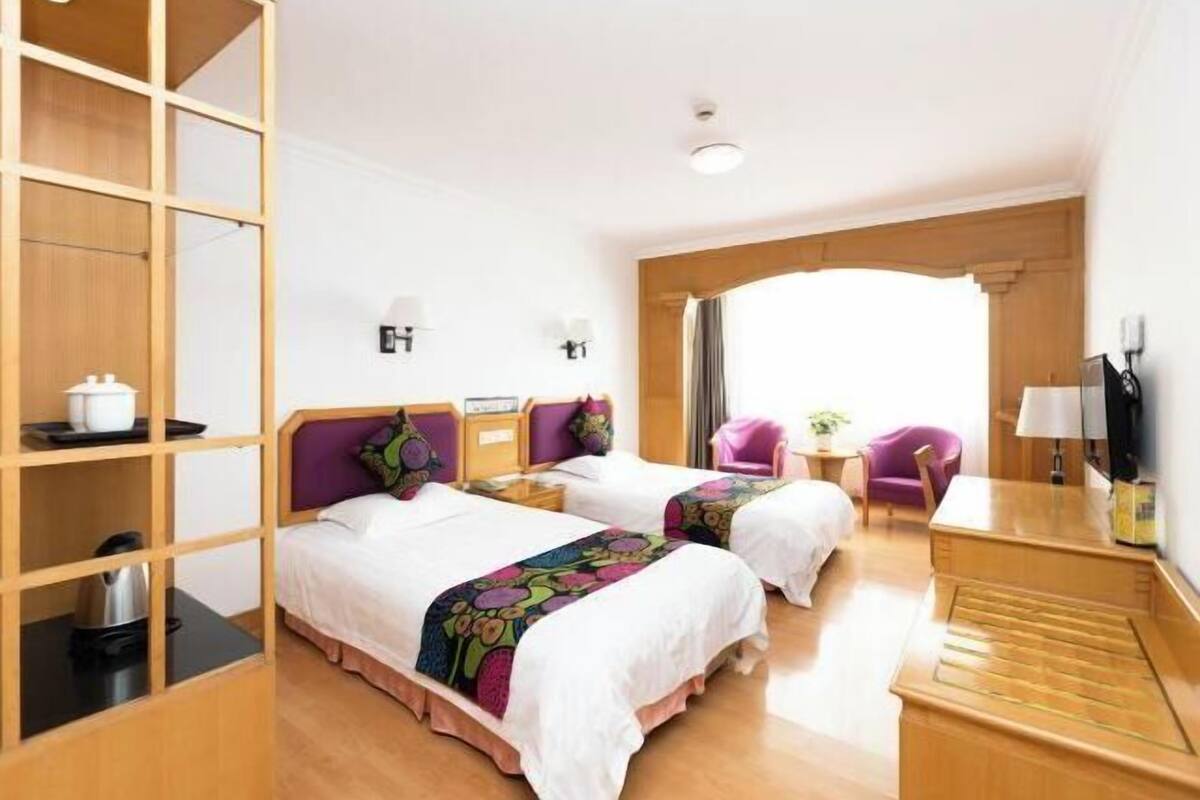 Une chambre d’hôtel avec deux lits, une armoire en bois, un bureau, une chaise et un téléviseur.