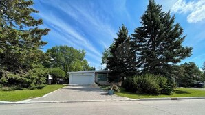 A residential house with a garage, driveway, and surrounding greenery.