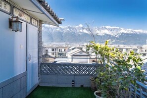 A balcony with a view of snow-capped mountains, a potted plant, and a traditional Japanese-style building.