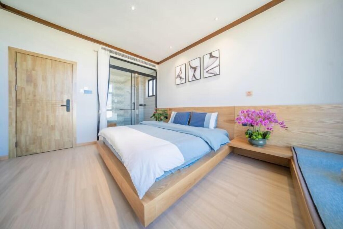 Ein modernes Schlafzimmer mit einem Holzbett, einer Glasdusche und einer Holztür.