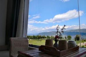 A room with a view of mountains, a chair, and a table with a vase and containers. - Dali Liwan Seaview Inn (Dali City)