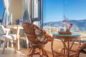 A room with wicker furniture, a table, and a view of mountains. - Dali Liwan Seaview Inn (Dali City)