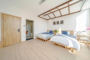 Ein Schlafzimmer mit zwei Betten, einem Oberlicht, Holzboden und einer Holztür.