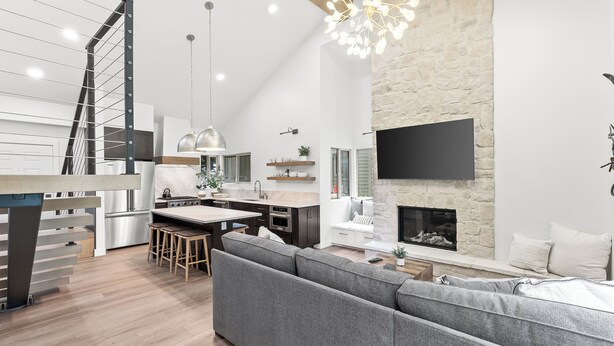 A modern kitchen with a stone fireplace, a dining area, and a living room with a grey sofa. - Creekside 3B/3B Townhome - 1 Block to Ski Lift! (Park City)