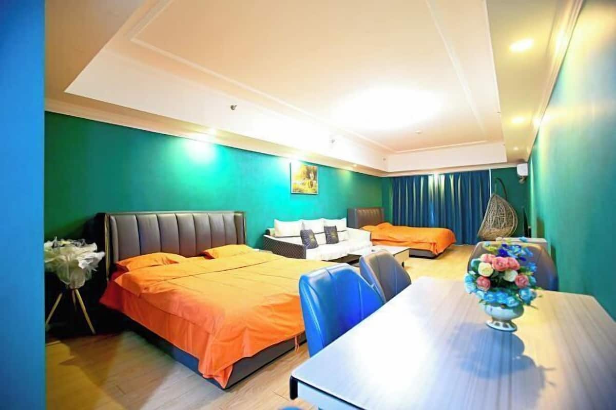 A hotel room with two beds, a dining table, and a vase of flowers.