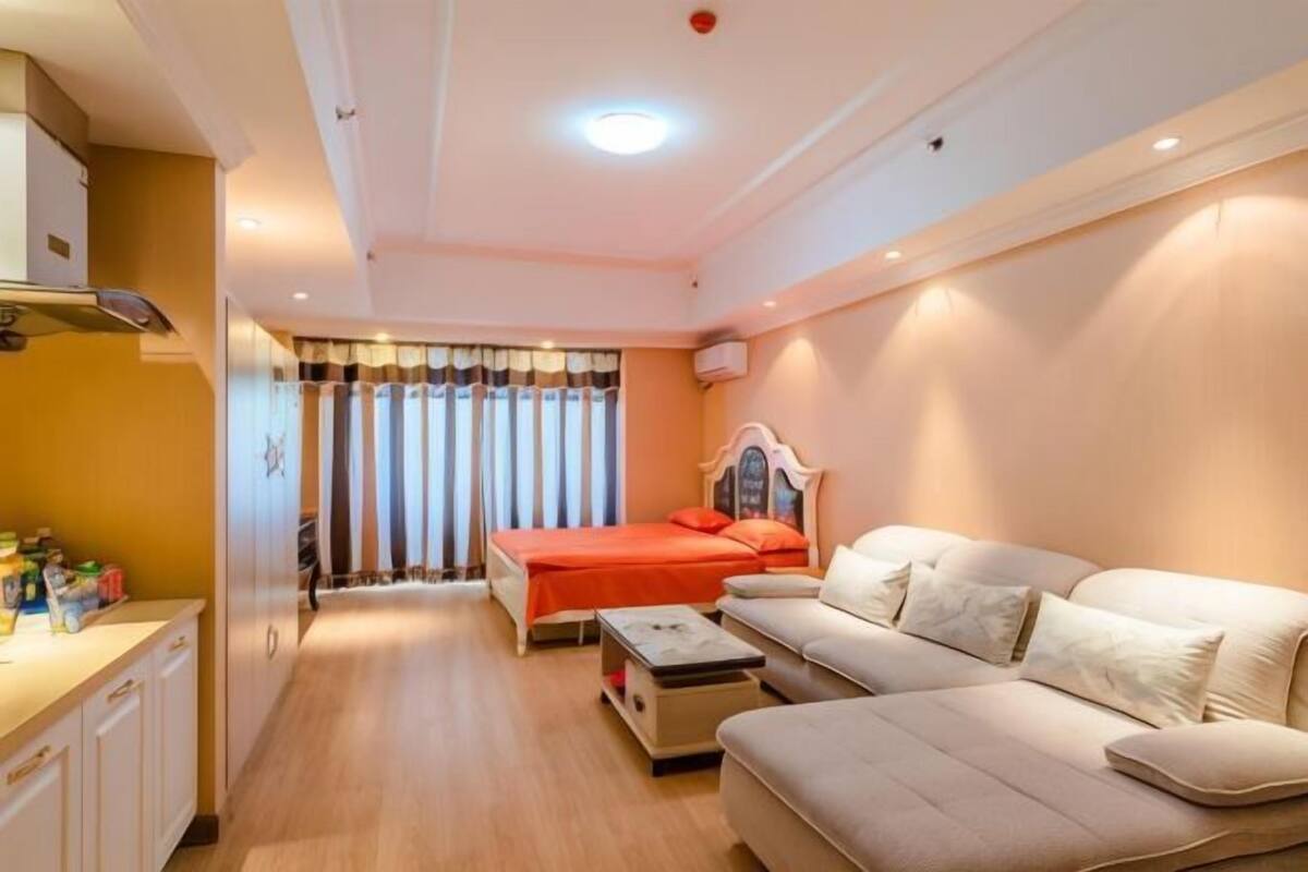 A bedroom with a bed, a sofa, a small table, and a window with curtains.