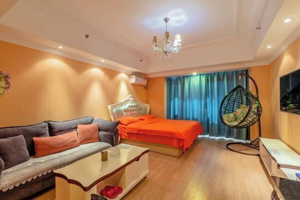 A hotel room with a bed, sofa, hanging chair, and a TV.