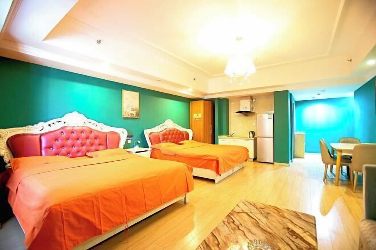 A hotel room with two beds, a dining area, and a kitchenette.