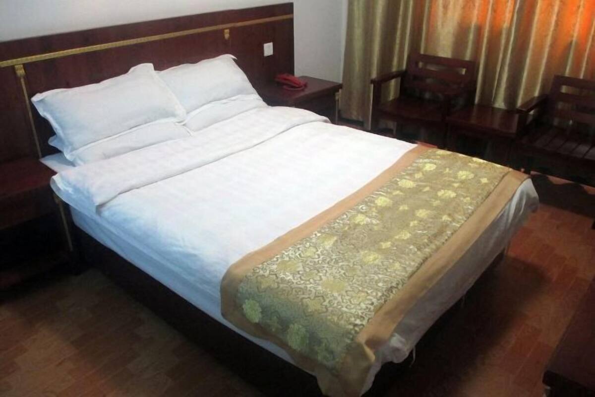 A neatly made bed with white linens, a decorative bedspread, and a wooden headboard.