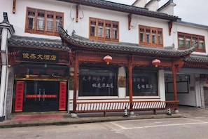 A traditional Chinese building with a tiled roof, wooden beams, and a signboard. - Junjie Hotel, Luxian County (Jing County)