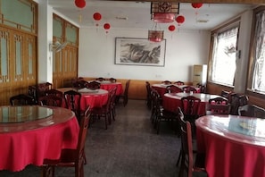 Un restaurant avec des tables rondes recouvertes de nappes rouges, des chaises en bois et des lanternes rouges.