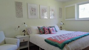 A bedroom with a bed, two bedside tables, a chair, and wall art. - Relaxing Birdsong Bungalow (Port Dover)