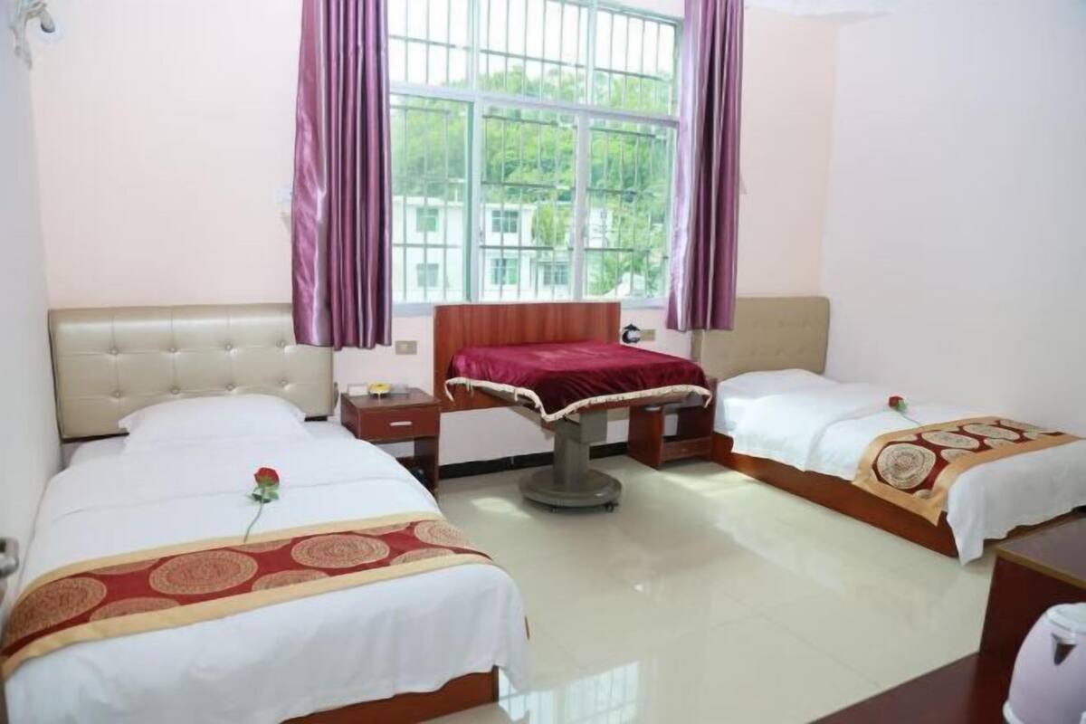 Una habitación de hotel con dos camas, una mesita de noche, una silla y una ventana con cortinas.