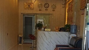 A lobby with a reception desk, a water dispenser, a clock, and a chandelier. - Pingtang Yuqi Hotel (Pingtang)