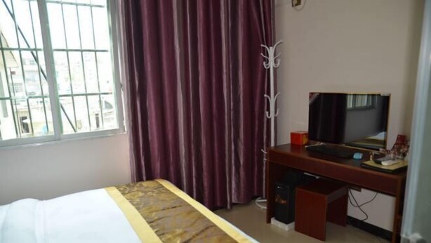 A hotel room with a bed, a desk with a computer, a TV, and a window with curtains. - Pingtang Yuqi Hotel (Pingtang)
