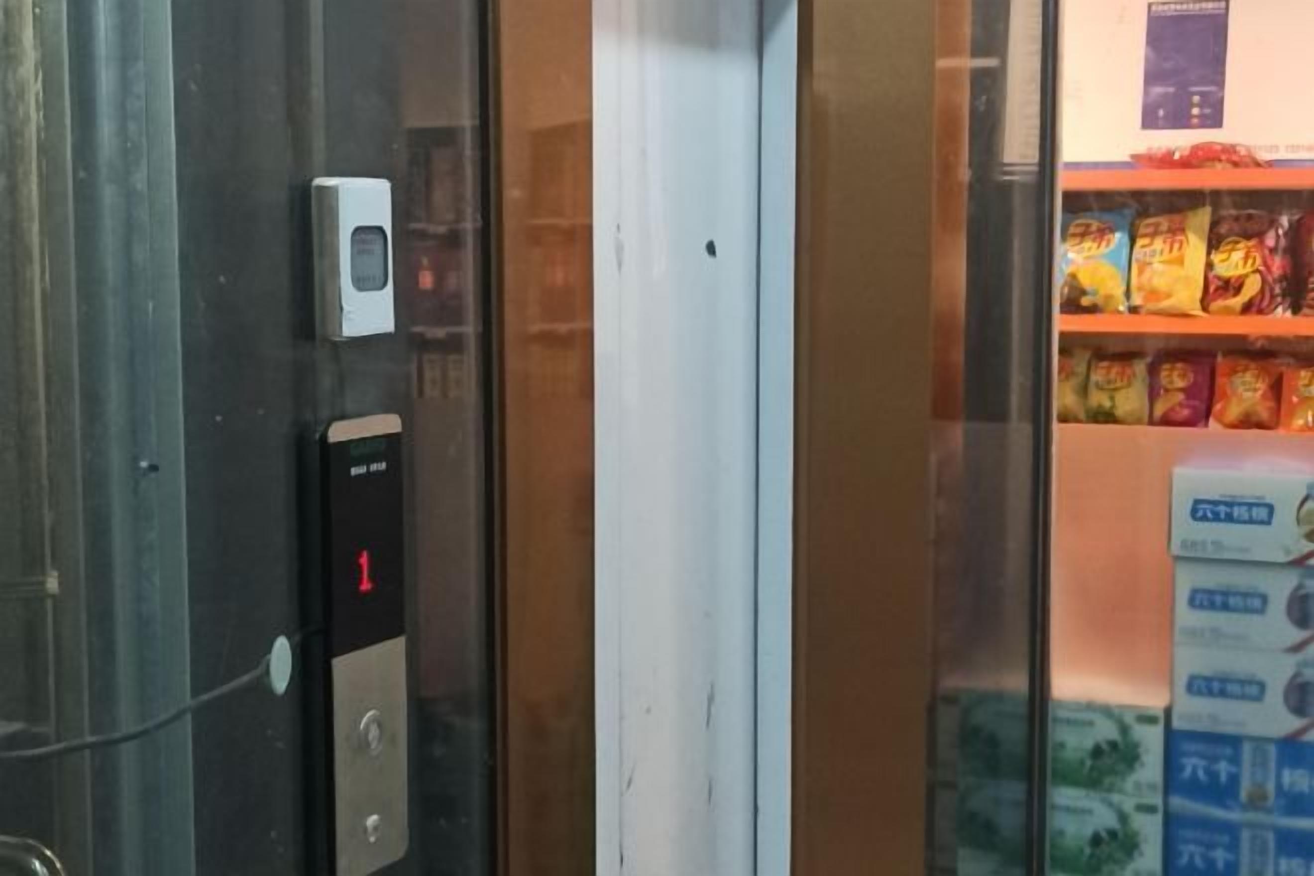 An elevator with a digital display indicating floor 1, a keypad, and a small device on the wall.