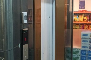 An elevator with a digital display indicating floor 1, a keypad, and a small device on the wall.