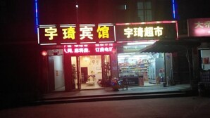 A storefront with illuminated signage, a visible entrance, and a display of goods outside. - Pingtang Yuqi Hotel (Pingtang)