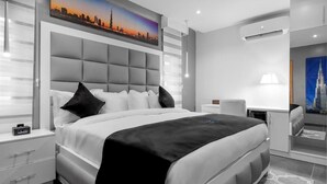 A modern hotel room with a large bed, a nightstand, a desk, and a chair.
