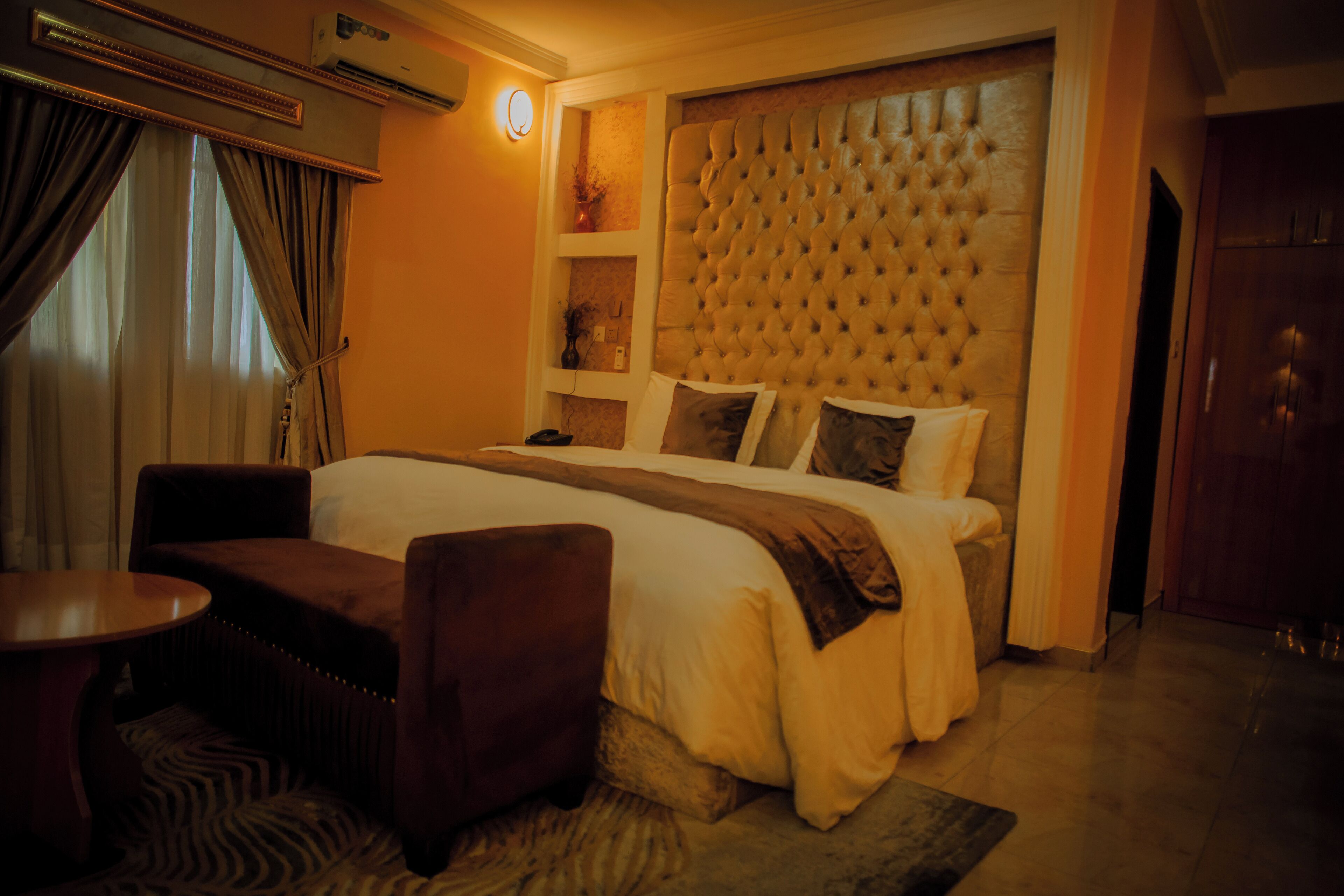 Una habitación de hotel con una cama grande, un sof á, una mesita y un panel decorativo en la pared.