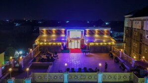 A building with a red carpet entrance, outdoor seating, and decorative lighting.