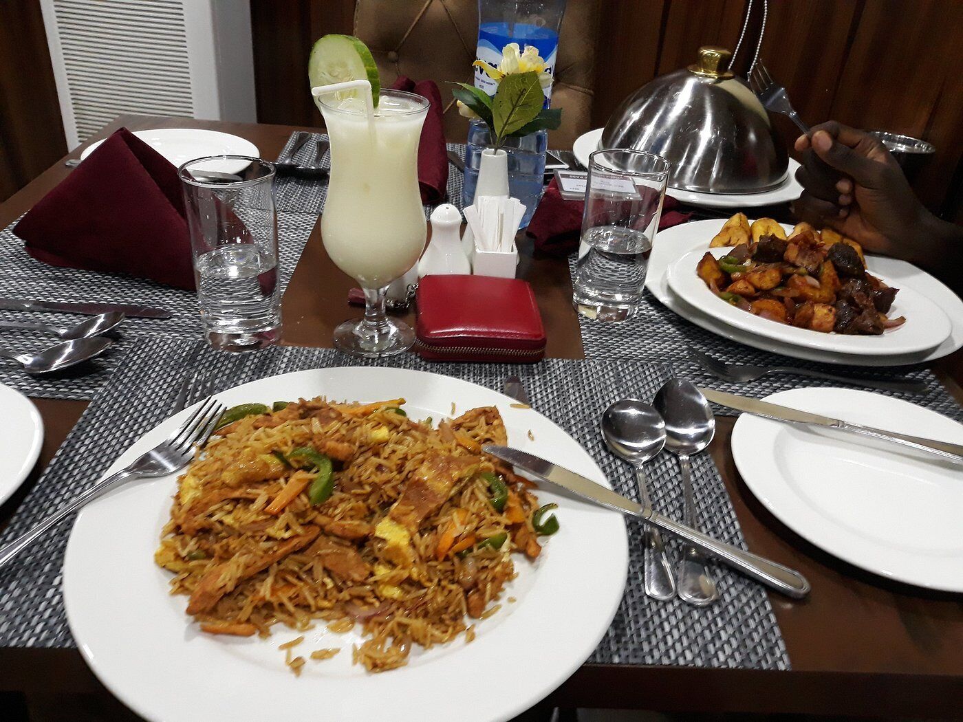 A dining table with a plate of fried rice, a glass of iced beverage, and a dessert.