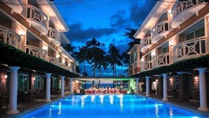 A hotel pool with a view of palm trees and a building facade with balconies. - Mandarin Island Hotel Boracay (Boracay Island)