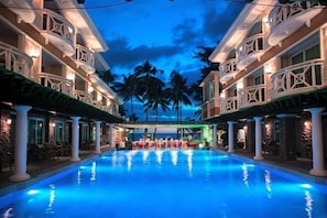 A hotel pool with a view of palm trees and a building facade with balconies. - Mandarin Island Hotel Boracay (Boracay Island)